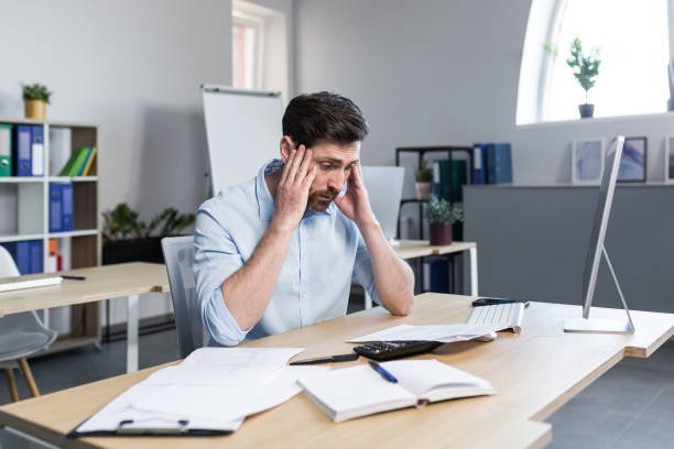 stressed corporate employee holding head in office cubicle. stressed corporate employee holding head in office cubicle.